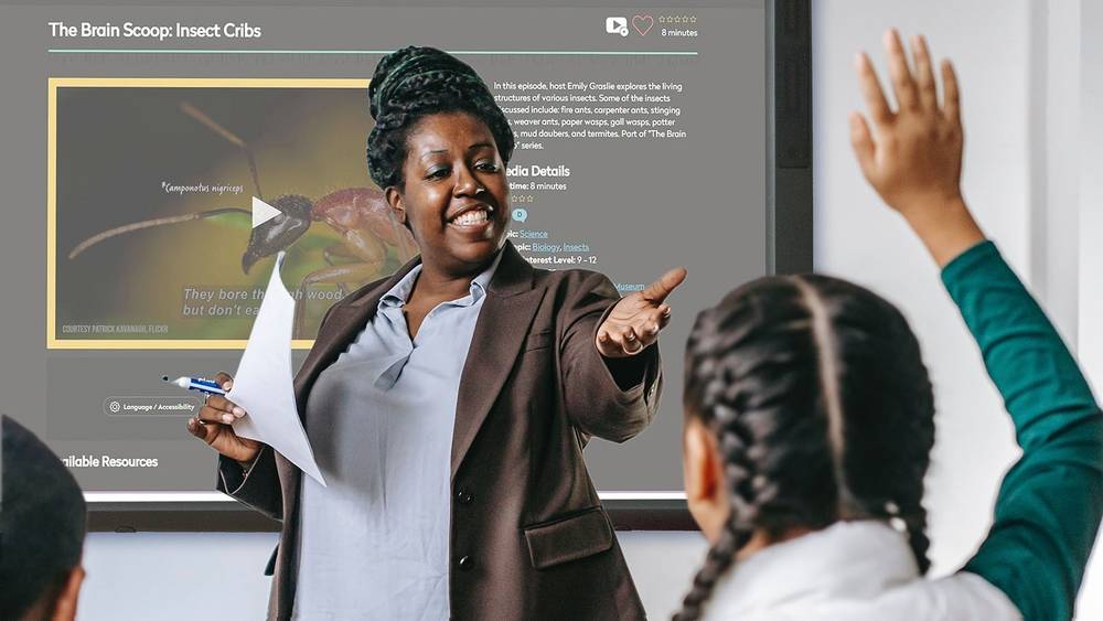 A teacher in a classroom acknowledges a student with her hand raised