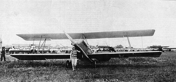 Black and white photo of Nellie Zabel Willhite standing with a single propeller biplane.