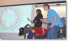 students sign along with a slide show on a large projection screen