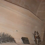 a massive tomb of rose-tinted marble bearing the carved name Louis Braille 1809-1852 and adorned by several metal sculptures and a plaque bearing Braille's name and likeness.