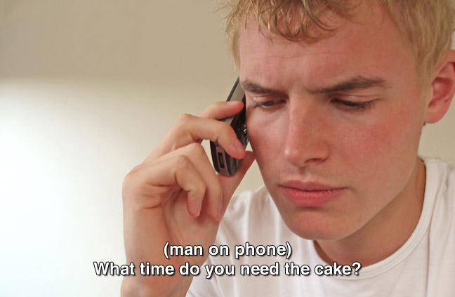 same teen from previous image speaking on cell phone. caption: (man on phone) When do you need the cake?