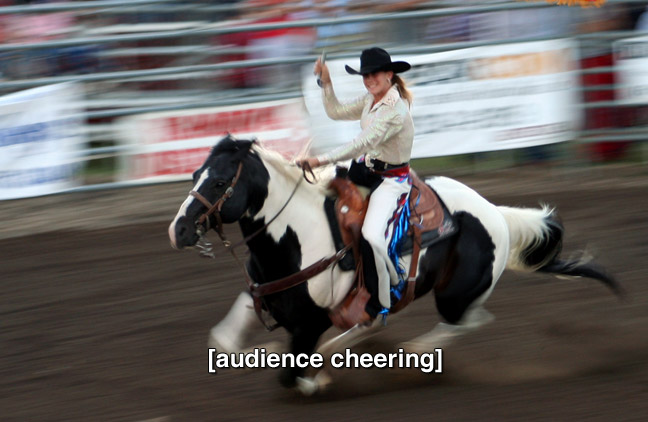 woman riding horse and twirling lasso at rodeo. caption: (audience cheering)
